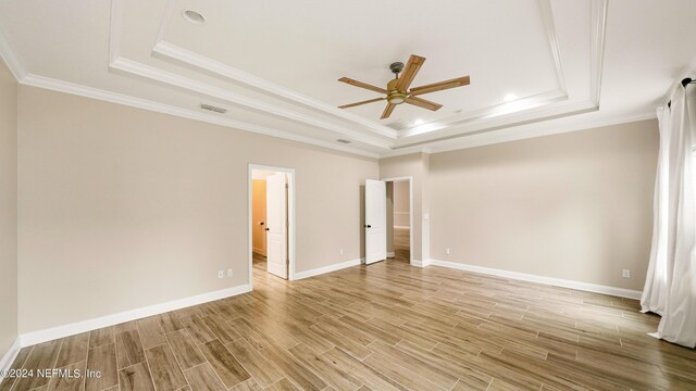 interior space featuring a raised ceiling, ceiling fan, and crown molding