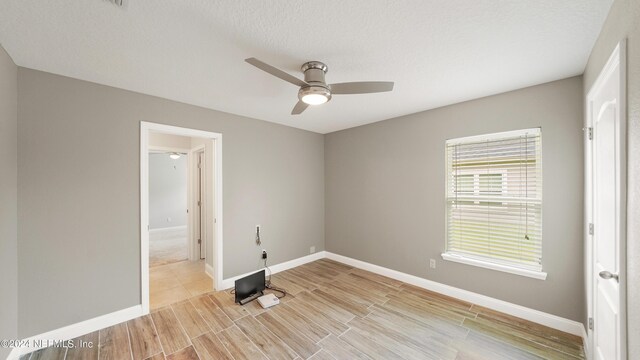 unfurnished room with ceiling fan and a textured ceiling