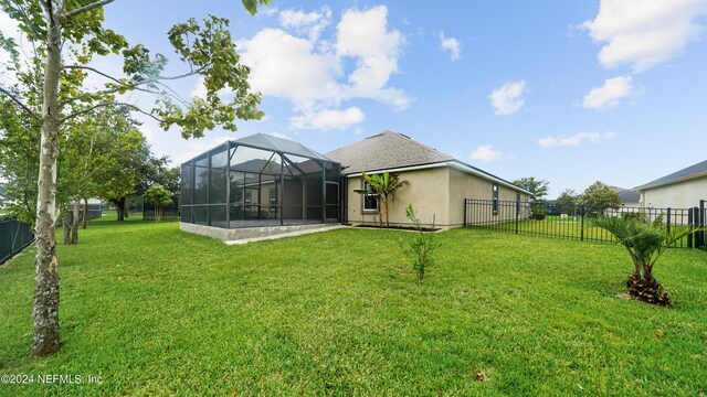 rear view of property with a lawn and glass enclosure