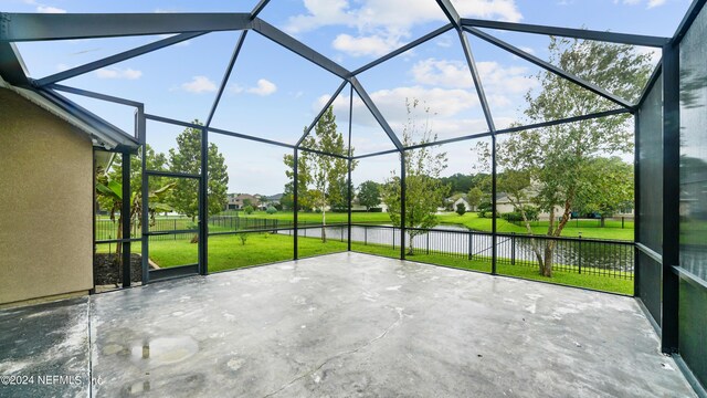 view of patio featuring glass enclosure and a water view