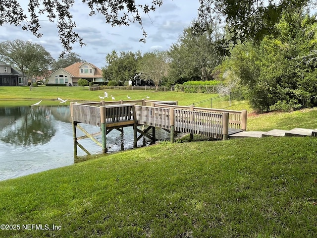 view of dock featuring a water view, a yard, and fence