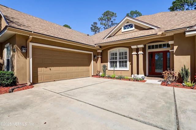 ranch-style home with roof with shingles, concrete driveway, and stucco siding