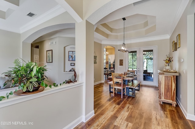 dining space featuring a tray ceiling, visible vents, ornamental molding, wood finished floors, and baseboards