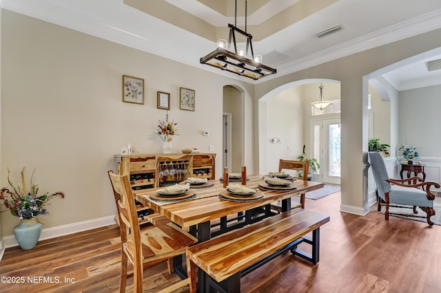 dining space with visible vents, arched walkways, crown molding, and wood finished floors