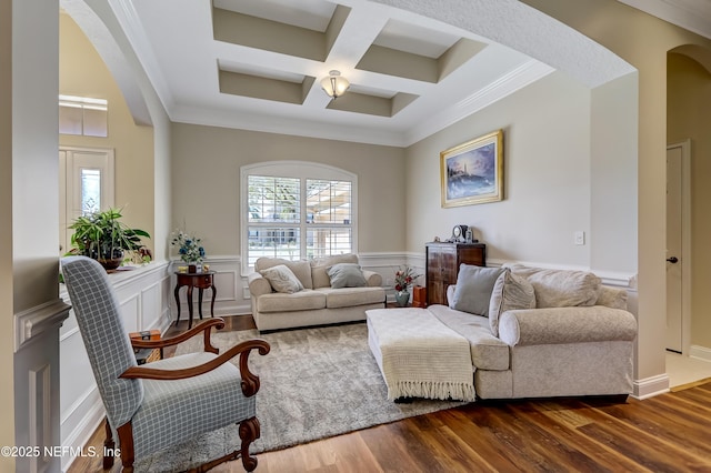 living area with dark wood-style floors, arched walkways, a wainscoted wall, ornamental molding, and coffered ceiling