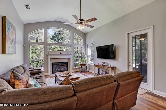 living area featuring baseboards, visible vents, lofted ceiling, ceiling fan, and wood finished floors