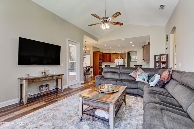 living area featuring arched walkways, visible vents, vaulted ceiling, wood finished floors, and ceiling fan with notable chandelier