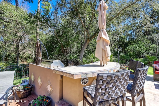 view of patio featuring an outdoor kitchen, fence, and grilling area