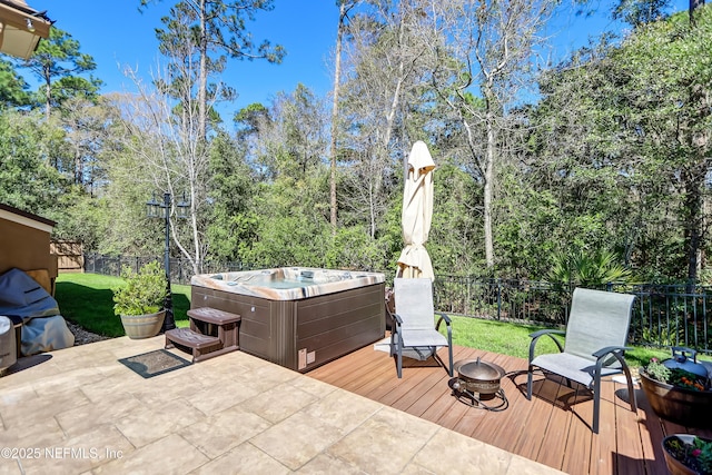 deck featuring a fire pit, a lawn, fence, and a hot tub