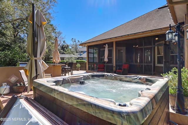 deck featuring a sunroom and a hot tub