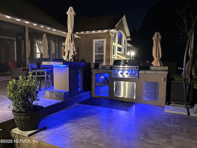 patio at twilight with a grill and an outdoor kitchen