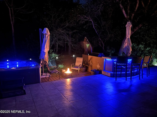 patio at twilight with an outdoor fire pit and a hot tub