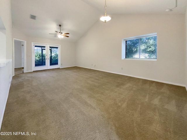 carpeted spare room featuring ceiling fan, vaulted ceiling, and french doors