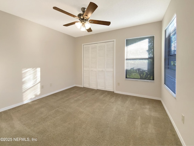 unfurnished bedroom featuring carpet flooring, ceiling fan, multiple windows, and a closet