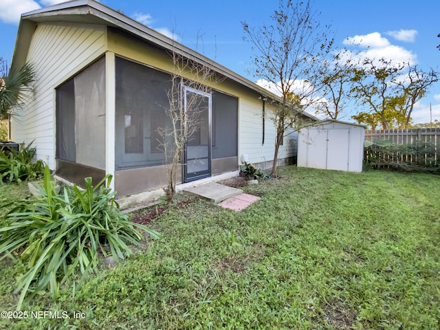 back of property with a sunroom, a yard, and a storage shed