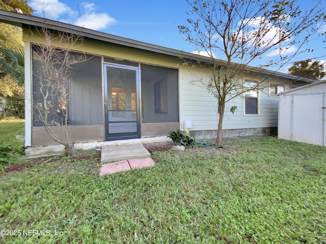 rear view of property featuring a sunroom and a yard