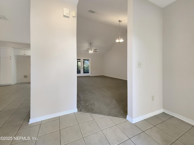 empty room with light tile patterned floors, ceiling fan with notable chandelier, and lofted ceiling