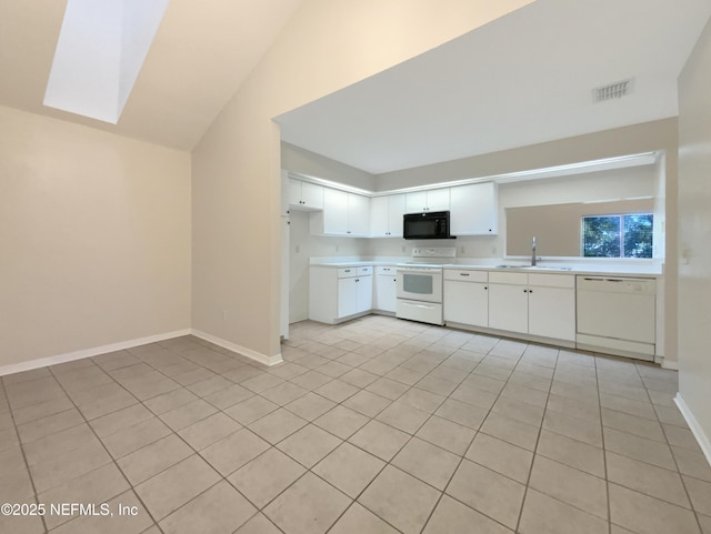 kitchen with sink, light tile patterned floors, lofted ceiling with skylight, white appliances, and white cabinets