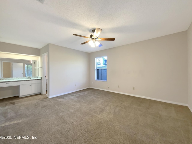 unfurnished bedroom featuring multiple windows, built in desk, light colored carpet, and ceiling fan