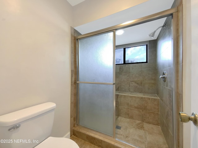 bathroom featuring toilet and a shower with door