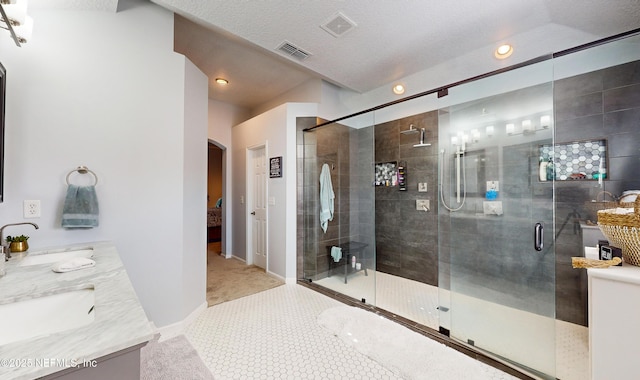 bathroom featuring tile patterned flooring, vanity, a shower with shower door, and a textured ceiling