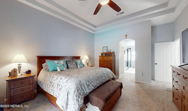 bedroom featuring light colored carpet, a raised ceiling, and ceiling fan