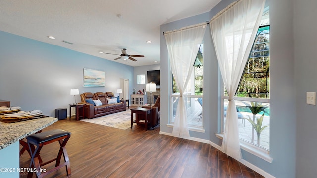 living room featuring ceiling fan and dark wood-type flooring