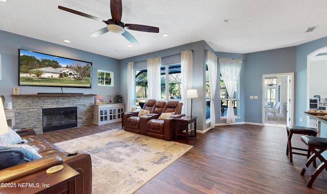 living room featuring a textured ceiling, ceiling fan, dark hardwood / wood-style flooring, and a fireplace