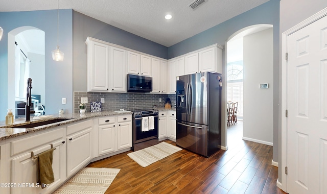 kitchen featuring white cabinets, appliances with stainless steel finishes, light stone countertops, and pendant lighting