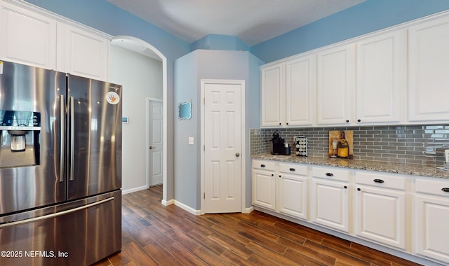 kitchen with stainless steel fridge, dark hardwood / wood-style flooring, tasteful backsplash, light stone counters, and white cabinets