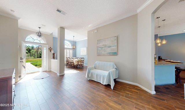 entrance foyer featuring a chandelier, a textured ceiling, and ornamental molding