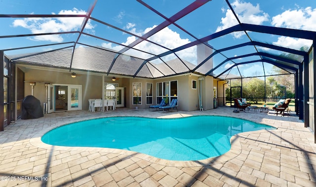 view of swimming pool with ceiling fan, a patio, and glass enclosure