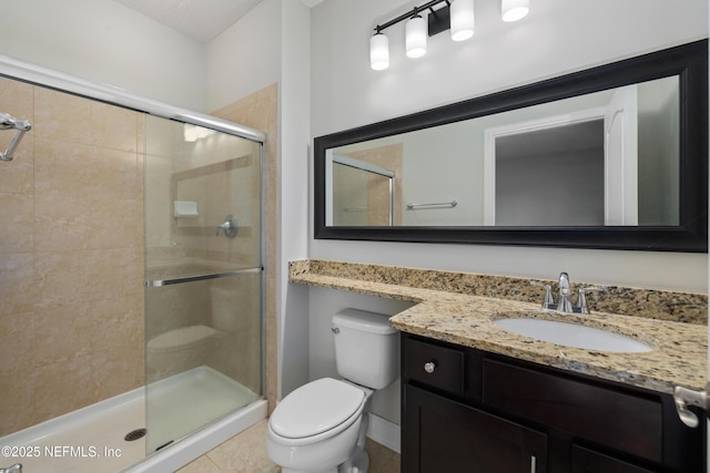 bathroom featuring tile patterned flooring, vanity, toilet, and a shower with shower door