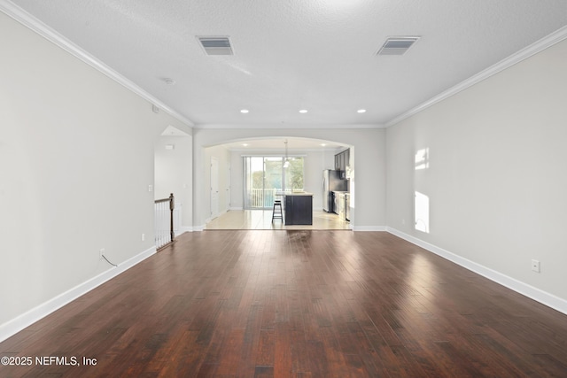 unfurnished living room with wood-type flooring, a textured ceiling, and ornamental molding