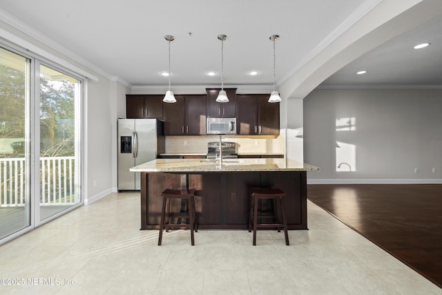 kitchen featuring pendant lighting, light stone countertops, crown molding, and stainless steel appliances