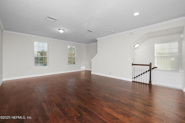 unfurnished room with a textured ceiling, crown molding, and dark wood-type flooring