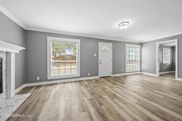 unfurnished living room with a textured ceiling, a premium fireplace, ornamental molding, and light hardwood / wood-style flooring