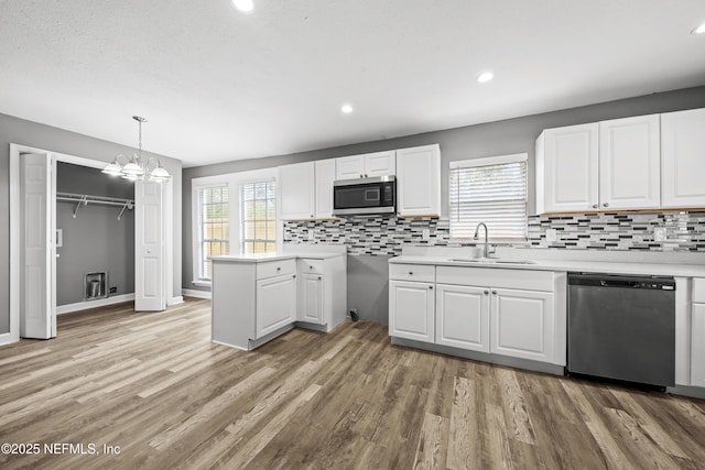 kitchen featuring white cabinetry, sink, a notable chandelier, pendant lighting, and appliances with stainless steel finishes