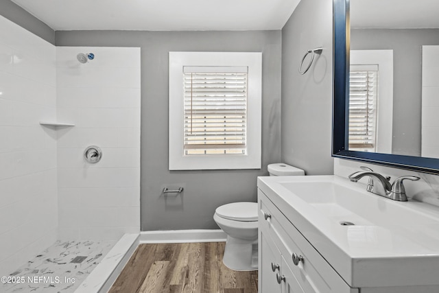 bathroom featuring vanity, toilet, wood-type flooring, and tiled shower