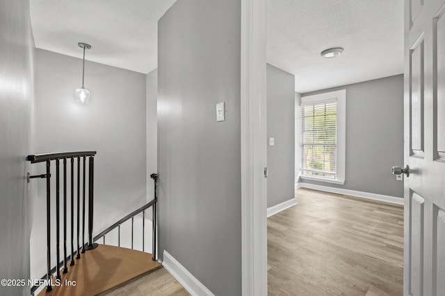 corridor featuring light hardwood / wood-style floors and a textured ceiling