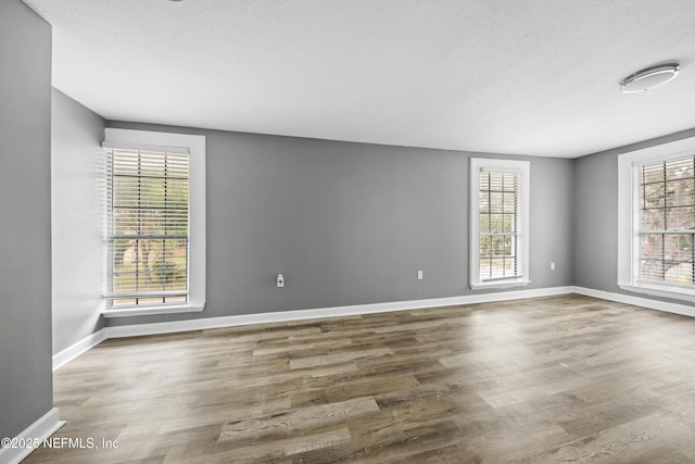 empty room with hardwood / wood-style flooring, a healthy amount of sunlight, and a textured ceiling