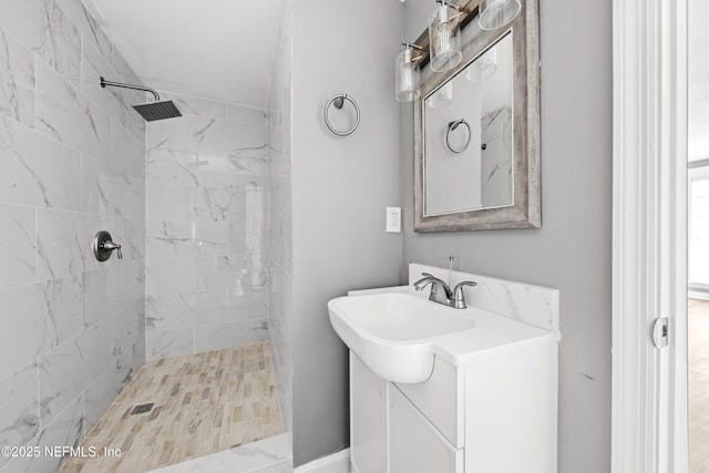 bathroom with a tile shower and vanity