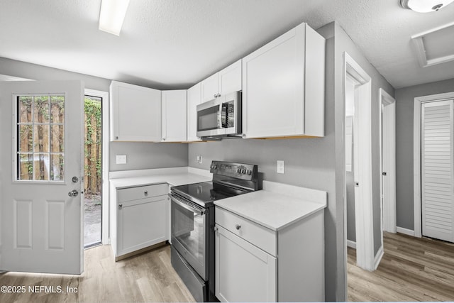 kitchen with electric range, light wood-type flooring, white cabinetry, and a textured ceiling