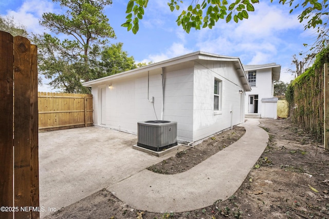 view of side of home with central AC unit and a patio