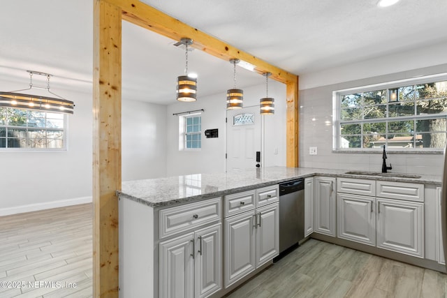 kitchen with light stone countertops, dishwasher, sink, kitchen peninsula, and decorative light fixtures