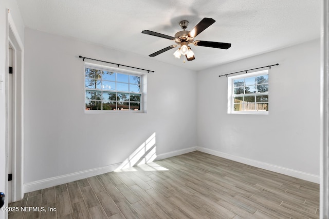 empty room with ceiling fan, light hardwood / wood-style flooring, and a textured ceiling