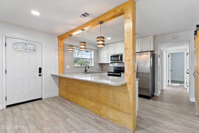 kitchen featuring kitchen peninsula, light stone countertops, stainless steel appliances, decorative light fixtures, and white cabinets