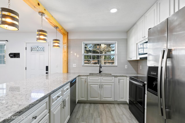 kitchen featuring decorative light fixtures, sink, white cabinetry, and stainless steel appliances