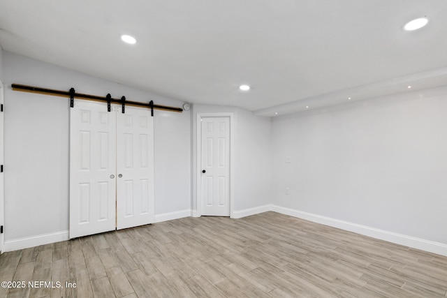 basement with a barn door and light hardwood / wood-style flooring