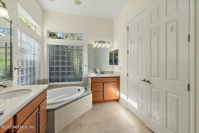 bathroom with vanity, tiled bath, and tile patterned flooring